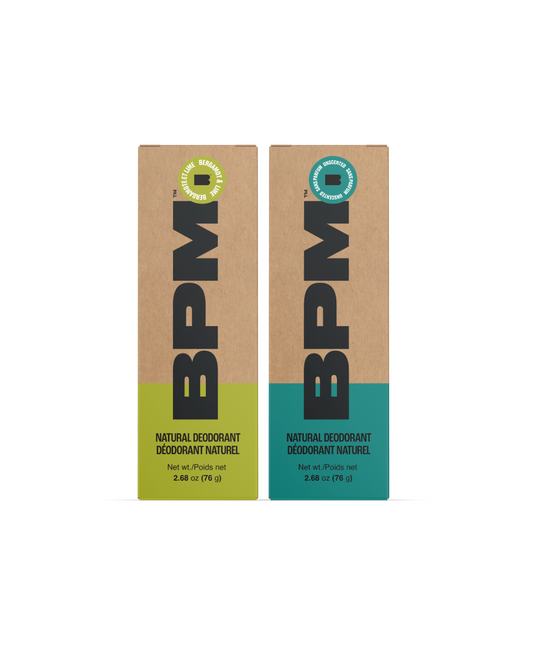 Two BPM natural deodorant boxes (Unscented and Bergamot & Lime) standing upright on a white background, one with a yellow-green lower section (Bergamot & Lime) and one with a teal lower section (Unscented). 